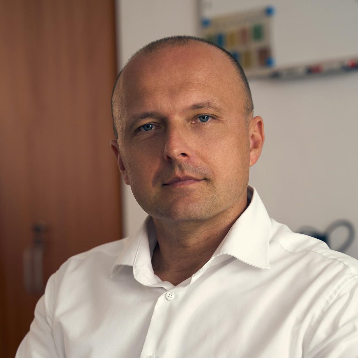 Confident professional posing for a portrait in a modern office environment.