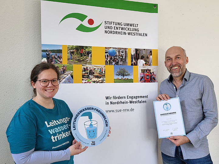Frank Griesel von der Stiftung Umwelt und Entwicklung Nordrhein-Westfalen freut sich über die Auszeichnung als leitungswasserfreundlich, die von Tine Wecker von a tip: tap übergeben wird.